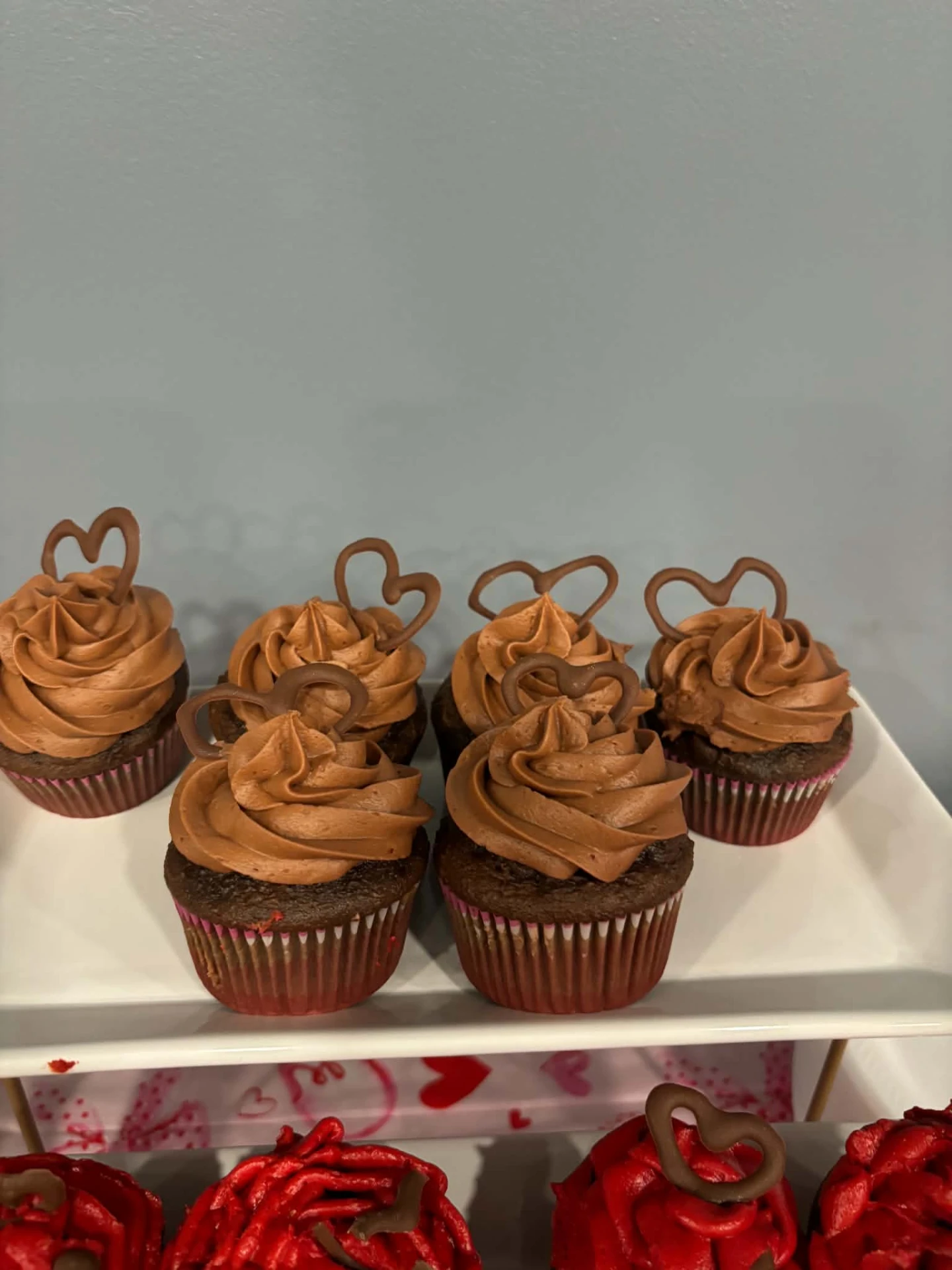 Chocolate cupcakes topped with chocolate hearts on a white platter